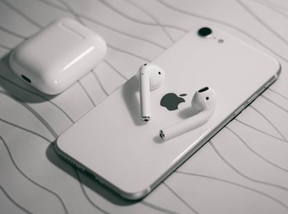 Auriculares AirPods al lado de un teléfono iPhone