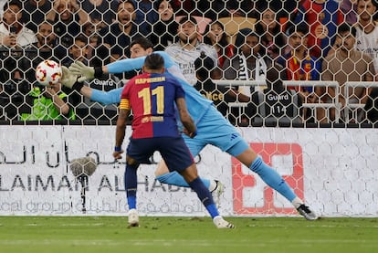 El guardameta belga Thibaut Courtois, del Real Madrid, detiene el lanzamiento del delantero brasileño del FC Barcelona Raphinha.
